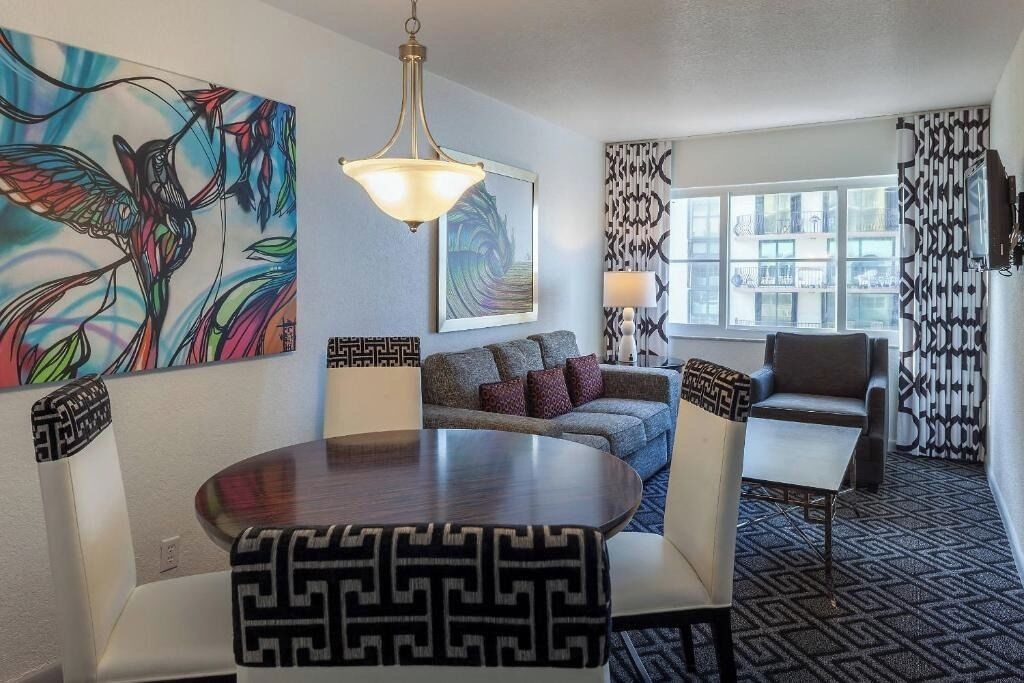 A modern living room with a round dining table, a sofa, a chair, and a large abstract painting.