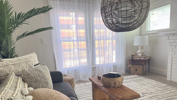 A living room with a sofa, a coffee table, a hanging light fixture, and a window with curtains. - 253 Upper Chic Boho Retreat NEW RENO (Erie)