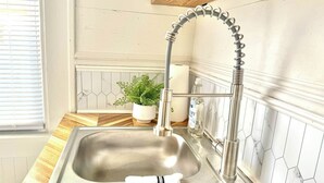 A kitchen with a stainless steel sink, a wooden countertop, a potted plant, and a white tiled backsplash. - 253 Upper Chic Boho Retreat NEW RENO (Erie)