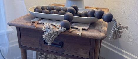 A wooden nightstand with a lamp, a bowl of round objects, and a woven basket.