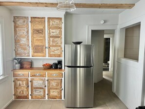 Eine Küche mit Holzausstattung, einem Edelstahlkühlschrank und einer Arbeitsplatte aus Holz mit Küchenutensilien.