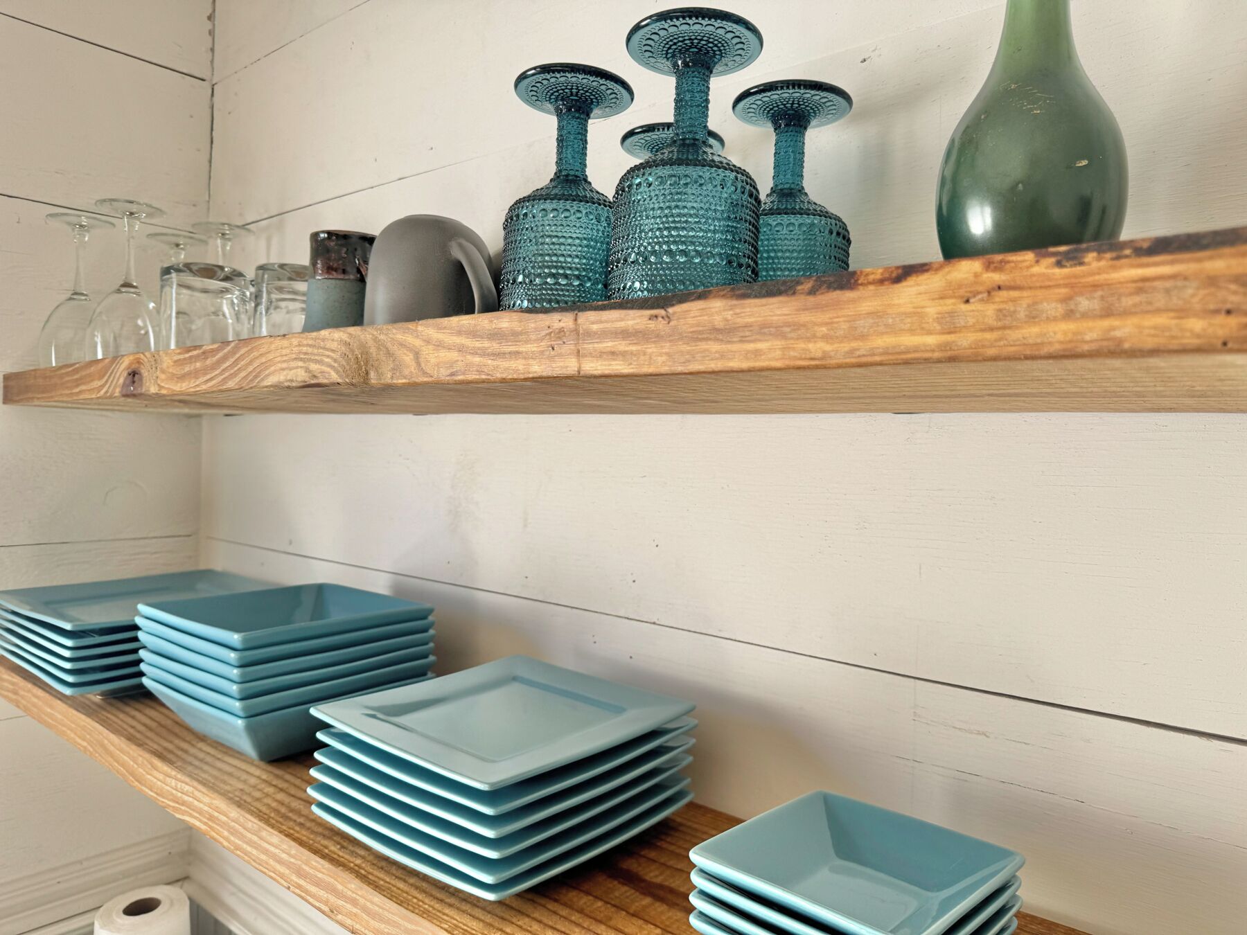 Une étagère en bois avec de la verrerie et des assiettes.