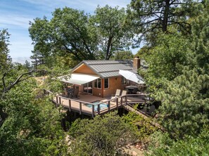 A cabin with a deck, outdoor seating, and a pool.