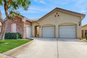 A two-story house with a stone facade, two garage doors, and a well-maintained lawn. - The Wayne House: Golf Course Views, Pool Access, Casita, and Minutes to Coachella (Indio)