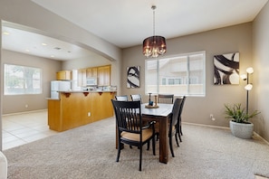 A spacious kitchen with a dining area, wooden cabinets, a central island, and a chandelier. - The Wayne House: Golf Course Views, Pool Access, Casita, and Minutes to Coachella (Indio)