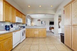 A kitchen with wooden cabinets, a built-in microwave, a stove, and a dishwasher. - The Wayne House: Golf Course Views, Pool Access, Casita, and Minutes to Coachella (Indio)