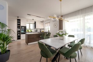 A modern kitchen with a central island, green upholstered chairs, and a marble dining table. - Villa Eufemia Perci (Istria - Poreč) (Poreč)