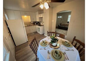 A dining area with a table set for four, a ceiling fan, and a kitchen in the background. - Convenient Wichita Townhome (Wichita)