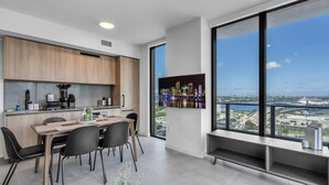 A modern kitchen with a dining area, large windows with a city view, and a built-in TV. - Modern High Rise Stay- 23 Floor Views (Miami)