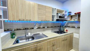 A kitchen with wooden cabinets, a stainless steel sink, and blue under-cabinet lighting.