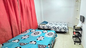 A room with two beds, a TV, and a small table with a lamp.