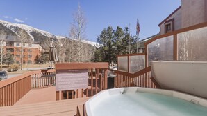 A hot tub on a wooden deck with a sign detailing rules, overlooking a mountainous area. - She305 Summit House East 1 Bedroom Condo (Copper Mountain)