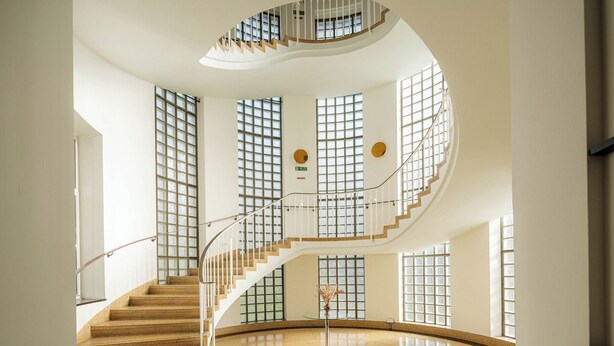 A spacious interior with a curved staircase, large windows, and a polished floor. - Bright 1BR in Central Clerkenwell (London)