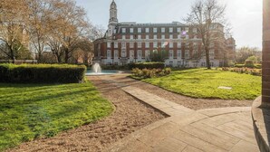 A large building with a prominent tower, surrounded by well-maintained lawns and a fountain. - Bright 1BR in Central Clerkenwell (London)