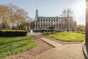 A large building with a prominent tower, surrounded by well-maintained lawns and a fountain. - Bright 1BR in Central Clerkenwell (London)