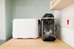A coffee machine and a white appliance, possibly a toaster, on a wooden countertop in a room with a light green wall and a white ceiling. - Beautiful 2BR Flat Near Highbury (London)