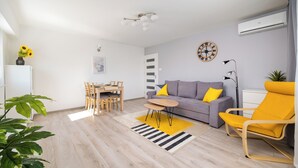 Ein modernes Wohnzimmer mit einer Couch, einem gelben Sessel, einem Esstisch und Stühlen.