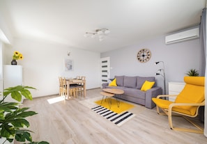 A modern living room with a sofa, yellow armchair, dining table, and chairs. - Chmielna Downtown Homely Apartment (Warszawa)