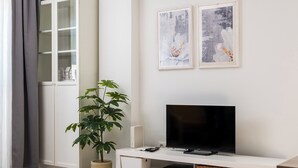 Ein modernes Wohnzimmer mit Fernseher, Stauraumelementen und Kunstwerken an der Wand.