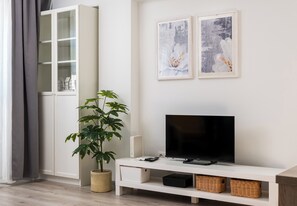 A modern living room with a TV, storage units, and artwork on the wall. - Chmielna Downtown Homely Apartment (Warszawa)