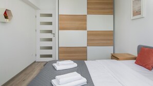 Ein modernes Schlafzimmer mit einem Bett, einem Nachttisch, einem Holzschrank und einem an der Wand montierten Regal.