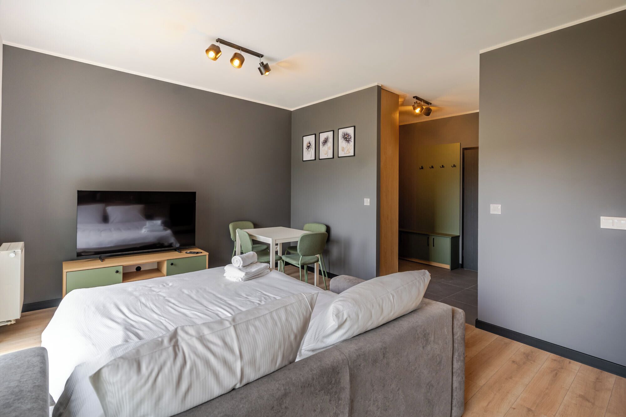 Una camera d'albergo moderna con un letto, televisione, angolo salotto e cabina armadio.