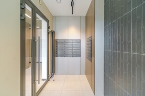 Un corridoio con una porta in vetro, una fessura per la posta a muro e una parete decorata.