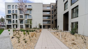 A modern multi-story building with a central courtyard, outdoor seating, and a gravel pathway. - Sowińskiego Modern Studio (Gliwice)