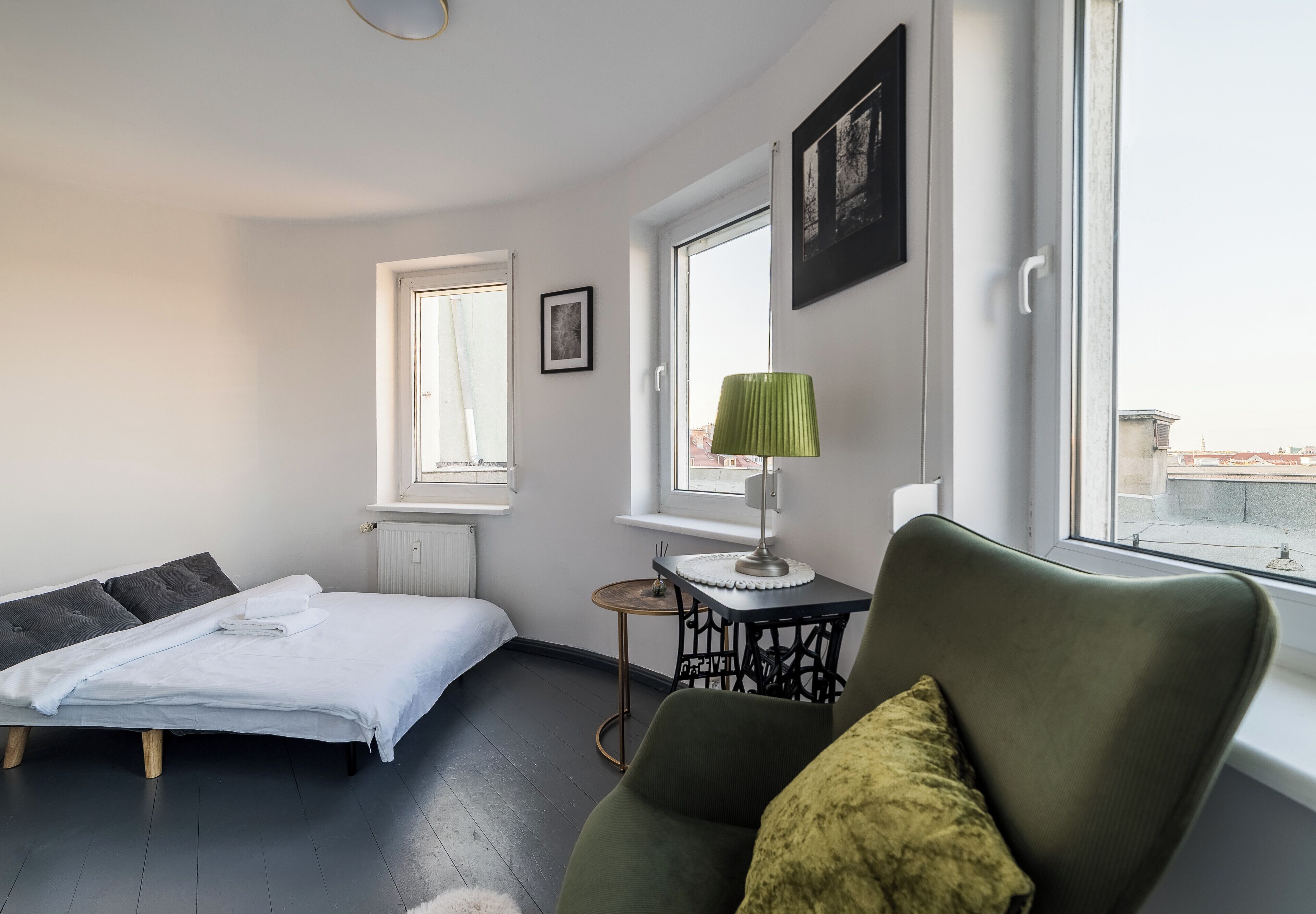 Une chambre à coucher avec un lit, une chaise, une table avec une lampe et une fenêtre donnant sur un beau paysage.