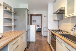 A modern kitchen with a stainless steel refrigerator, a gas stove, wooden countertops, and white cabinetry. - Mastalerza Spacious Apartment (Gliwice)