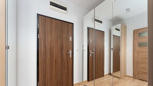 A hallway with wooden doors, a mirror, and a light fixture. - Rakowicka Charming Apartment with Garden (Kraków)