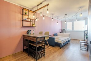 Ein kleines Zimmer mit Schreibtisch, Stühlen, einem Bett und einem Fenster.