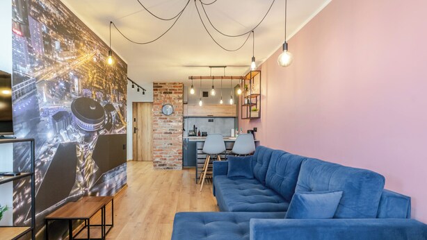 Ein modernes Wohnzimmer mit einem blauen Sofa, einem Holztisch und einer Stadtlandschaftsmalerei an der Wand.
