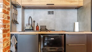 Eine kleine Küche mit Spüle, einem Kühlschrank und einer Holz Arbeitsplatte.