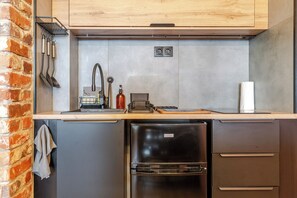 Eine kleine Küche mit Spüle, einem Kühlschrank und einer Holz Arbeitsplatte.