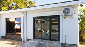 Un edificio moderno con ingresso tramite porta in vetro, patio in mattoni e condizionatore Samsung.