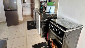 A compact kitchen with a refrigerator, microwave, stove, and oven.