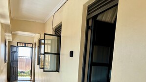 A corridor with tiled flooring, a door with a number '18' sign, and a window with a view of greenery.