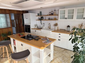 A kitchen with white cabinets, a wooden countertop, a sink, a stove, and a dining area with chairs. - SANTA MONICA HOUSE IN LA DEL VALLE FOR THE WORLD CUP (Ciudad de México)