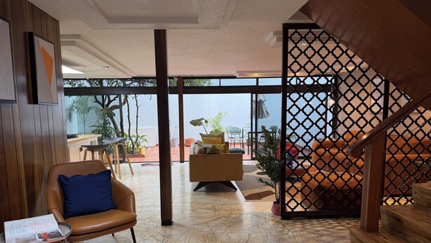 Un intérieur moderne avec un sol en marbre, une cloison en bois, un canapé et un escalier.