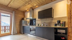 A modern kitchen with wooden beams, a large window, and a view of the outdoors. - La Seille - HAUTELUCE (HAUTELUCE)