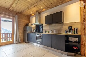 Eine moderne Küche mit Holzbalken, einem großen Fenster und Blick ins Freie.