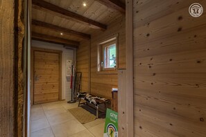 Ein Holzinterieur mit einem Bett, einem Kleiderhaken und einem Fenster.