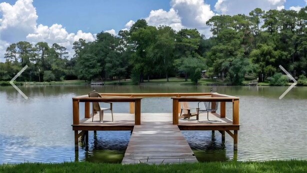 A wooden dock with chairs extending over a calm lake, surrounded by lush greenery and trees. - Peaceful Lake Guesthouse (Montgomery)