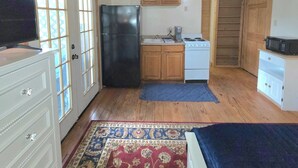 A compact room with a wooden ceiling, a refrigerator, a stove, a microwave, and a television. - Peaceful Lake Guesthouse (Montgomery)