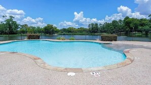 A swimming pool with a surrounding fence, trees, and a clear sky. - Peaceful Lake Guesthouse (Montgomery)