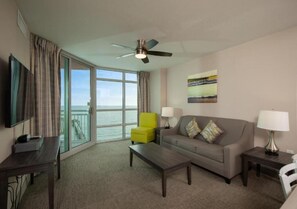 A hotel room with a sofa, armchair, coffee table, TV, and a balcony with a view. - Fantastic 2-bedroom condo with AC in North Myrtle Beach (North Myrtle Beach)