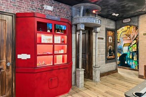 Ein roter Lagerraum mit Glastüren, eine Tür mit der Aufschrift 'Der Geheime Raum' und ein Schild für 'Gringotts'.