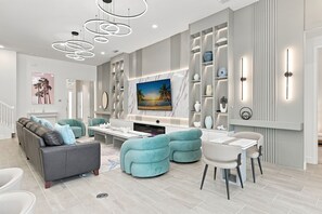 Una sala de estar moderna con un sofá, sillones, un televisor y una chimenea.