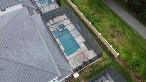 Un edificio residencial con piscina, terraza cubierta y jardín cercado.